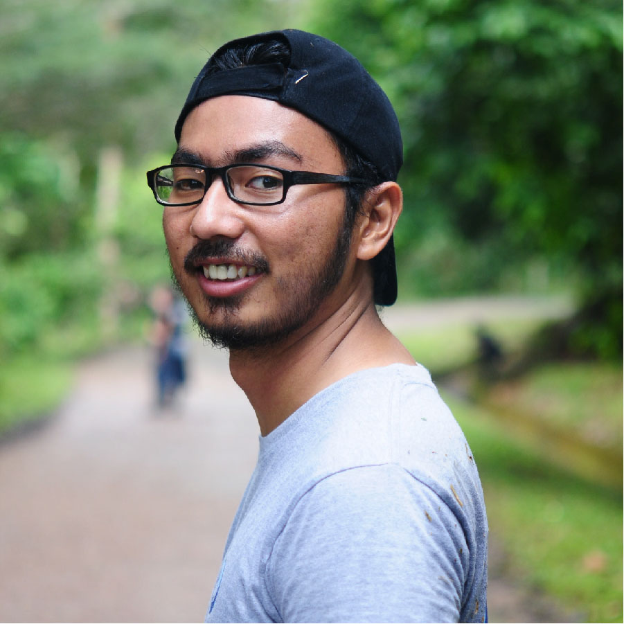 EDGE Fellow Muhammad Ichsan headshot, turning towards the camera with a blurred forest background